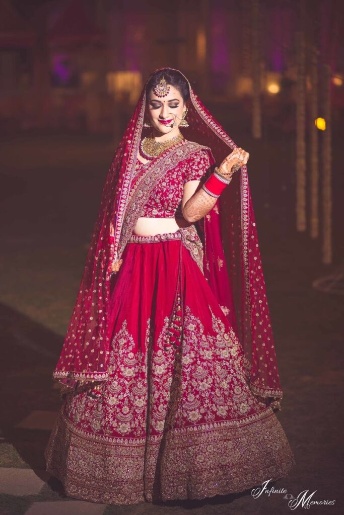 Photo of Bride in deep red bridal lehenga holding dupatta